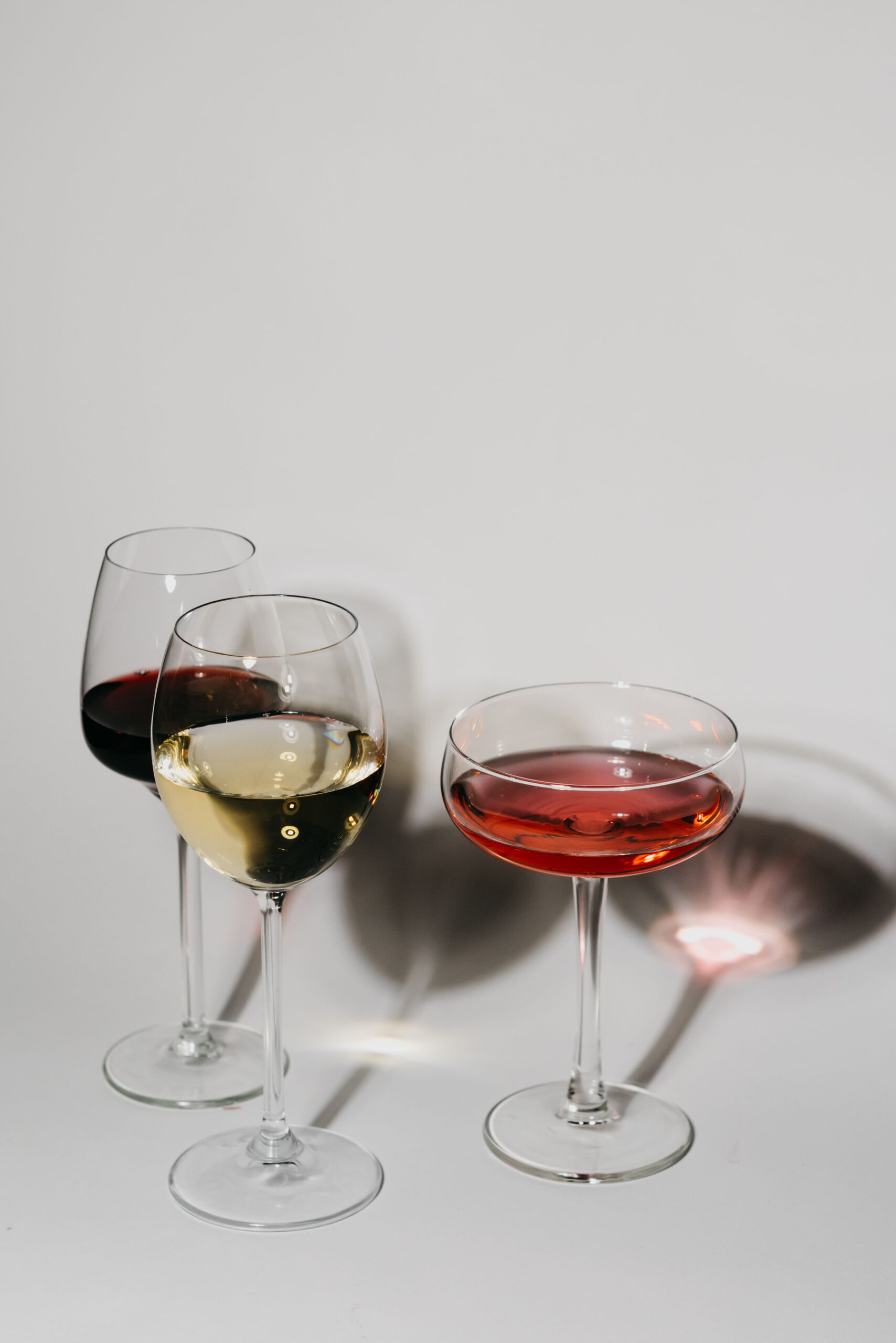 Glasses of red, white and rosé wine on a white table