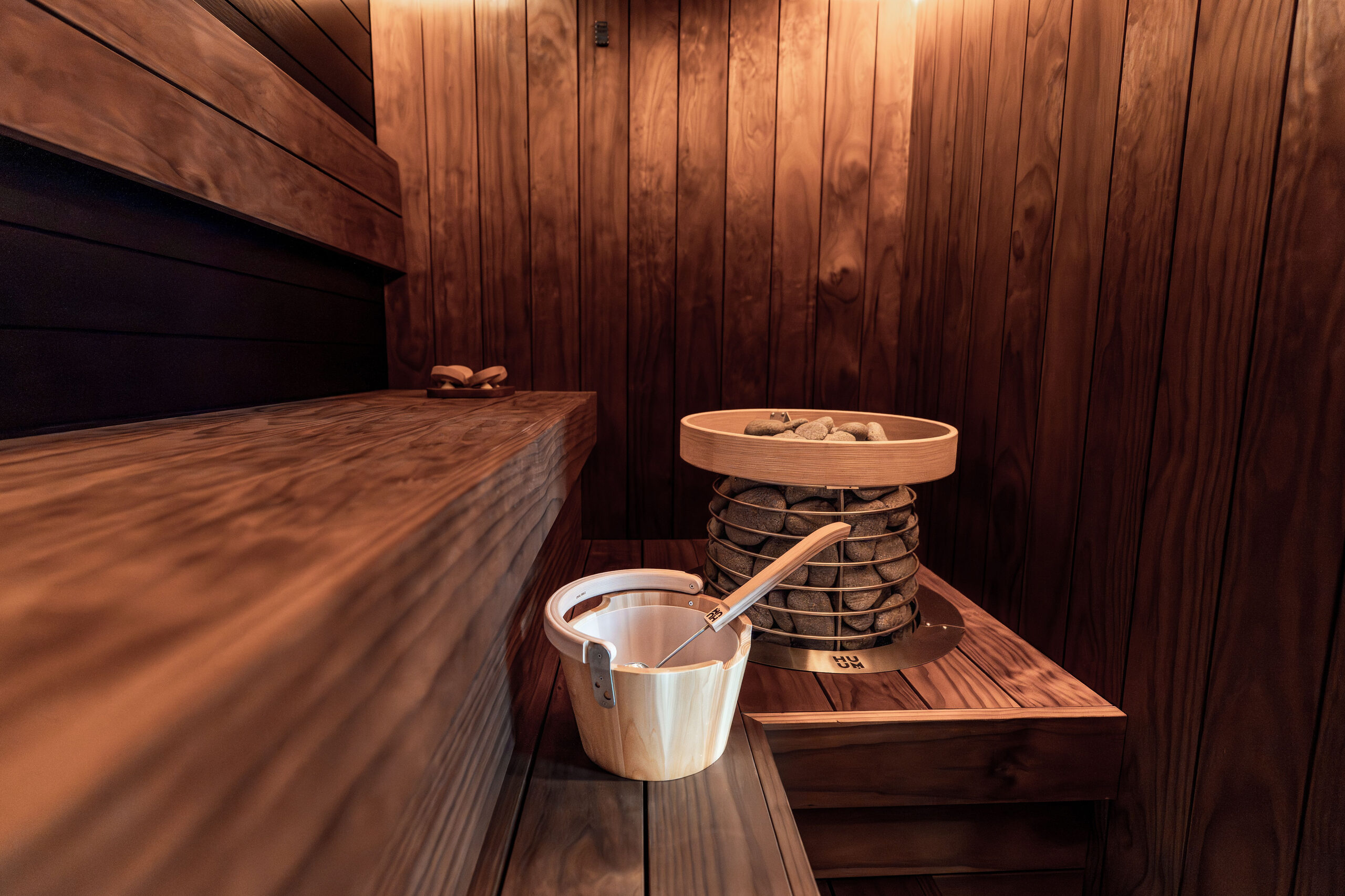 A wooden sauna with a bench, a stone stove and a wooden bucket with a ladle
